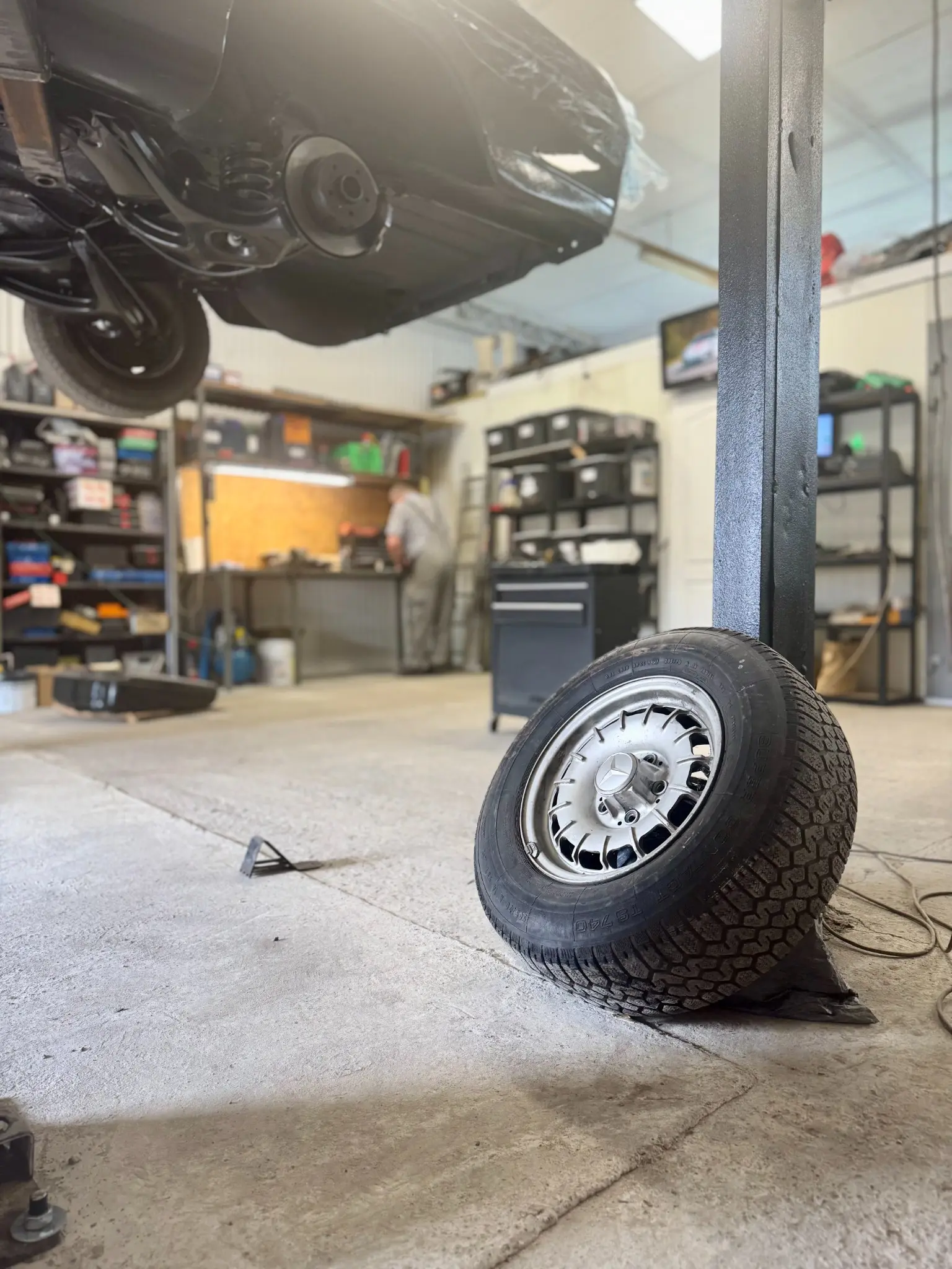 Koło samochodu oparte o podnośnik w warsztacie Odra Serwis